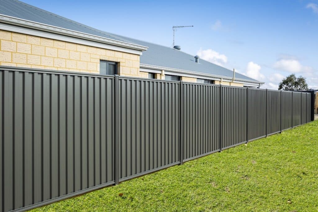 Installed dark charcoal steel privacy fence beside a residential property.