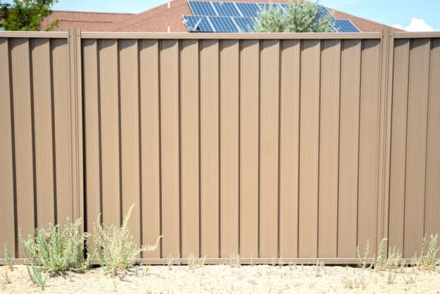 Installed warm earth-tone steel privacy fence panel run in a residential yard.