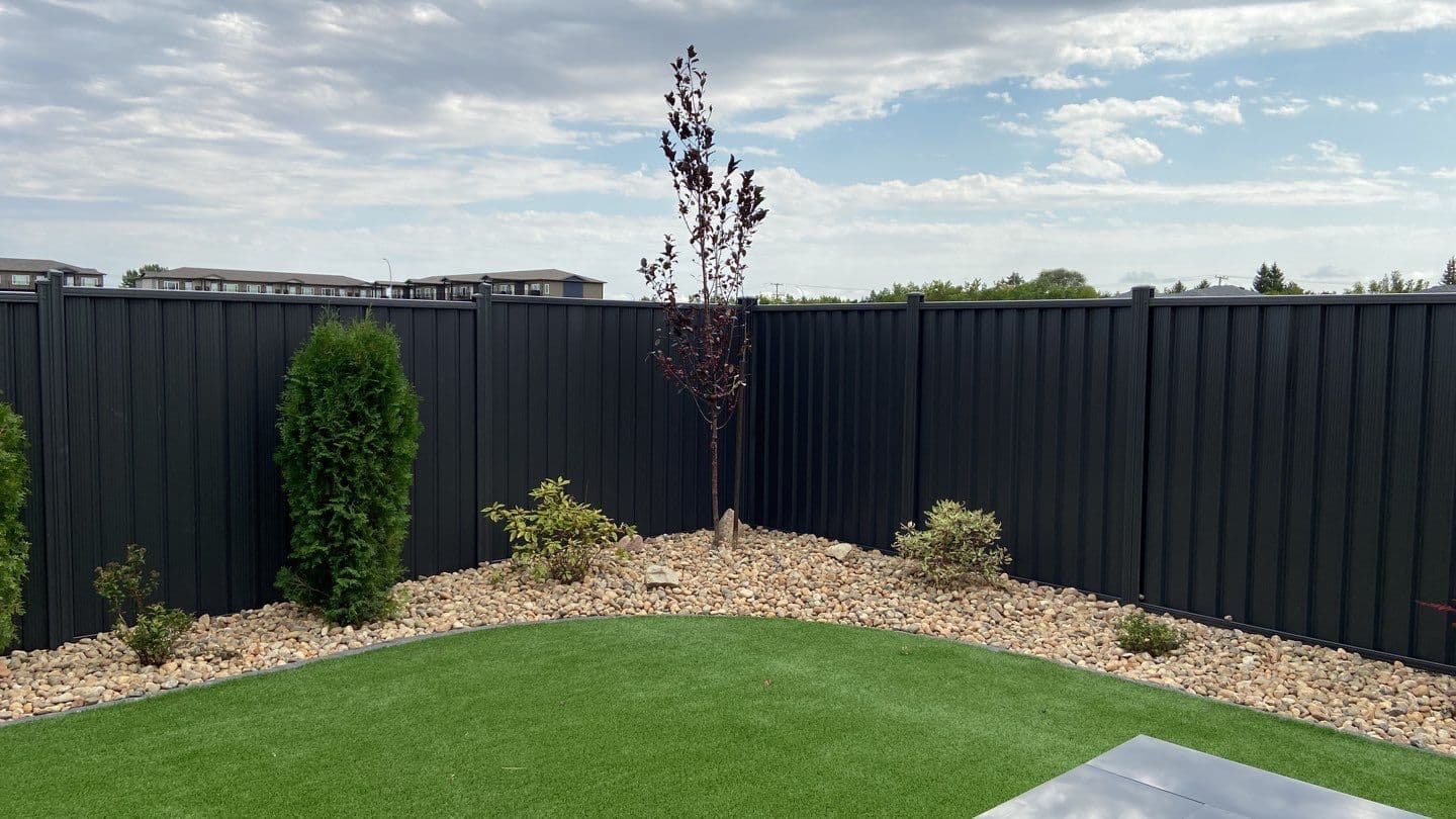 Installed black steel privacy fence enclosing a landscaped yard.