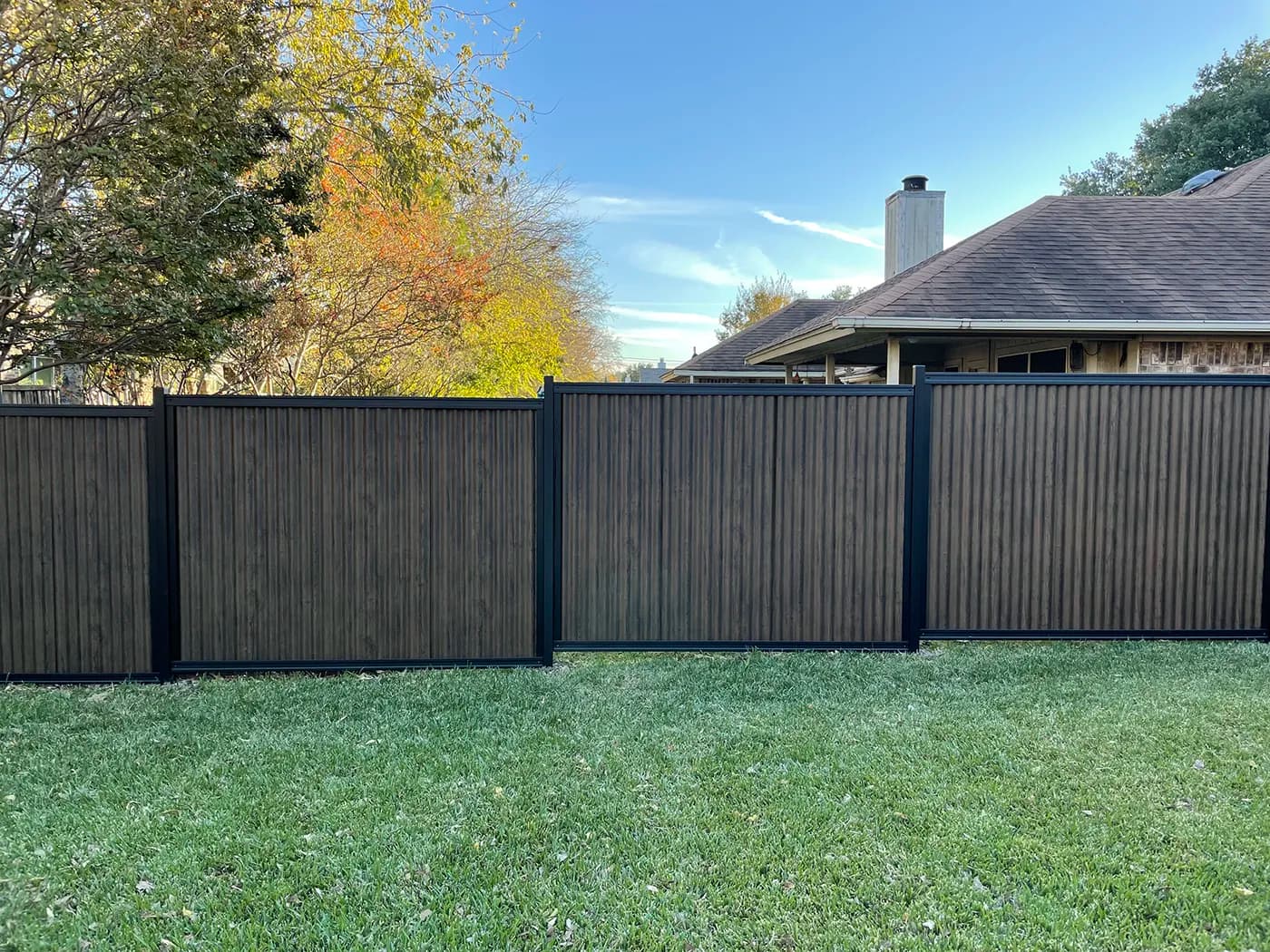 Dark Wood wood-look designer metal fence panel in a Perimtec framed system.