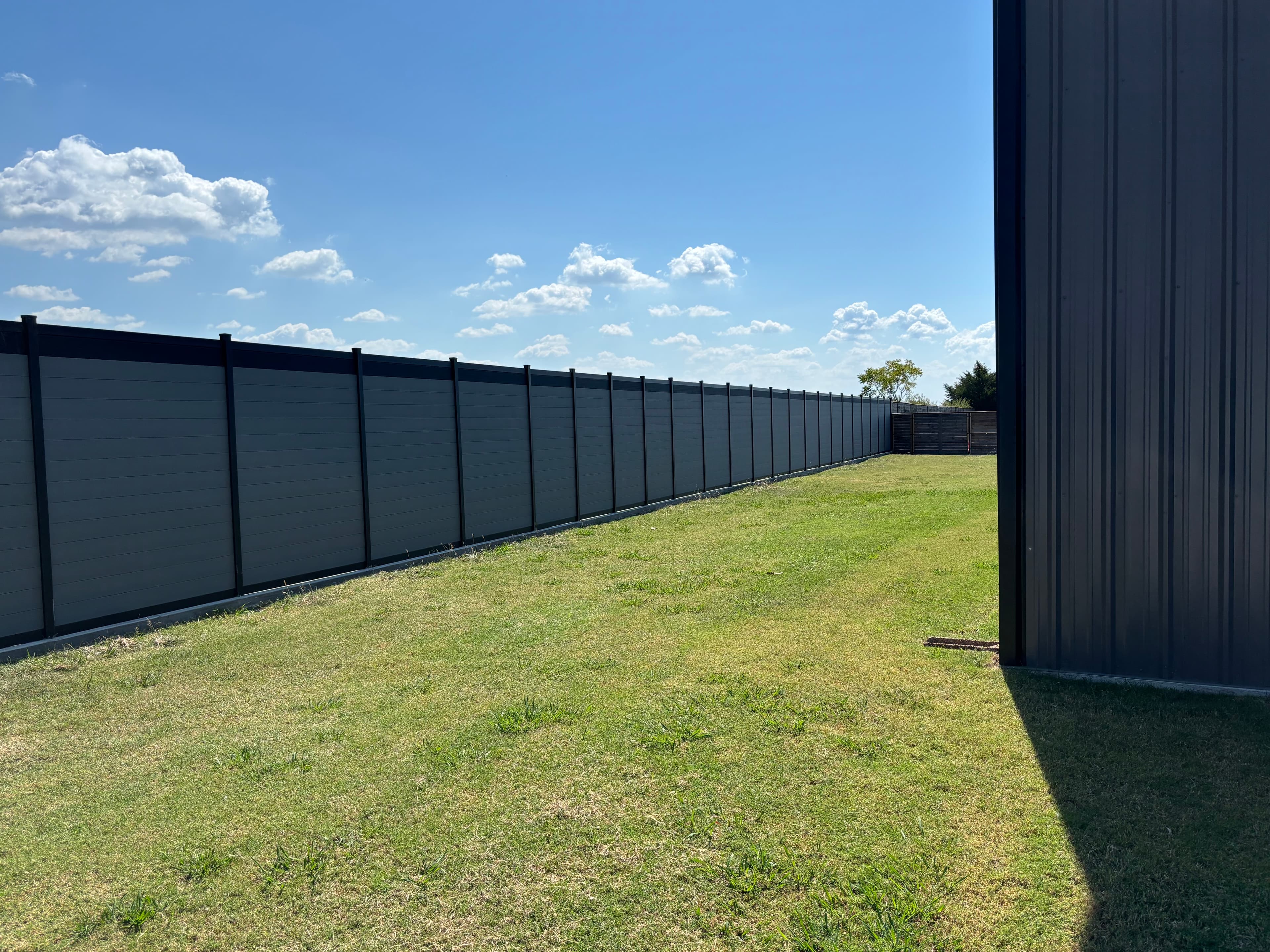 Finished aluminum frame privacy fence run with gray horizontal sections.